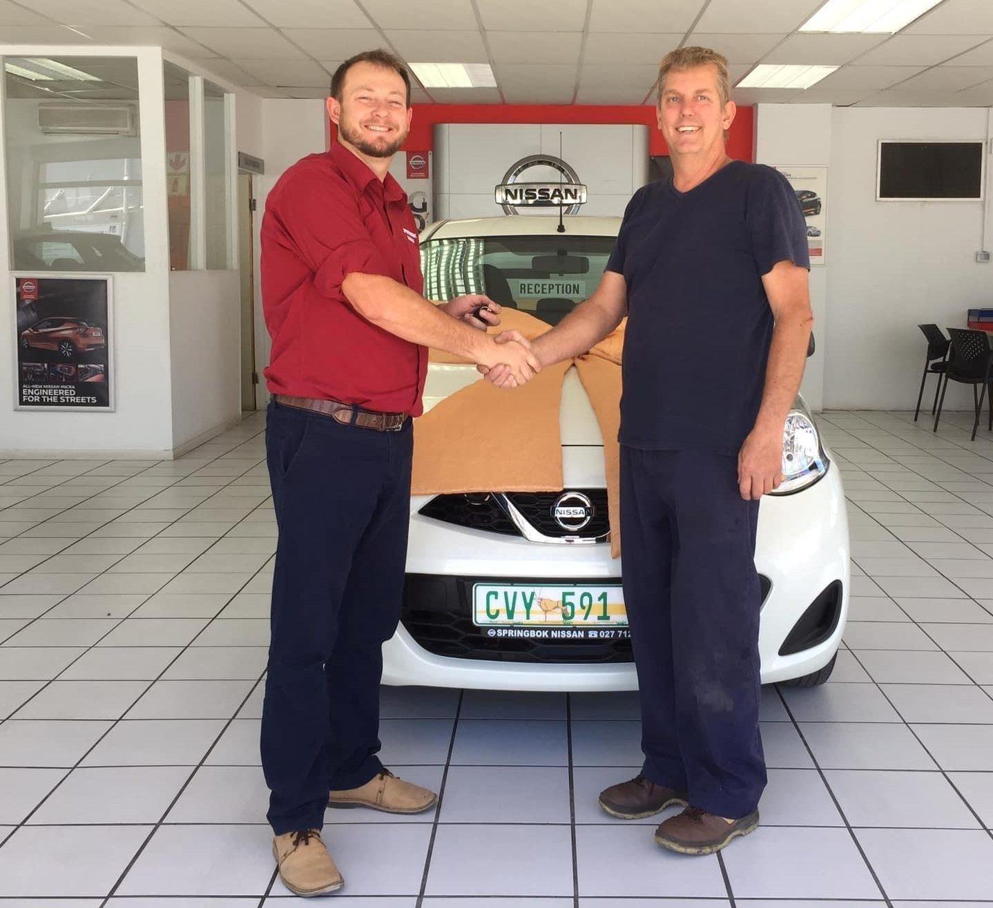Kobus Spangenberg (left) handing over a vehicle to a client, Lionel Richards.