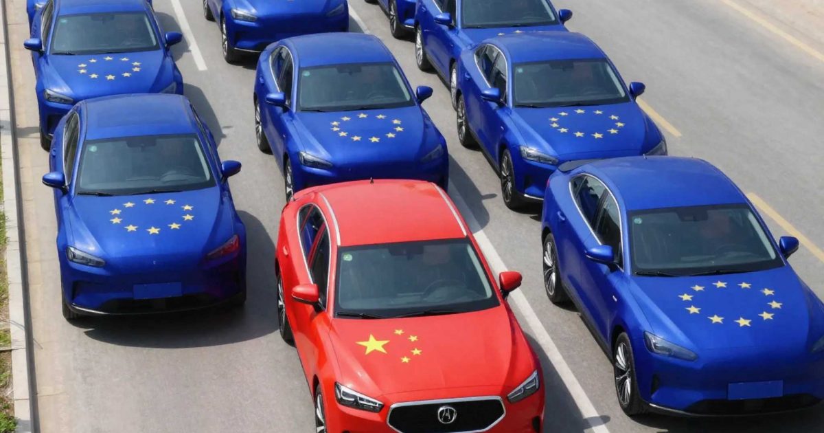 A row of hybrid cars parked in a dealership lot with the European and Chinese flags visible in the background.